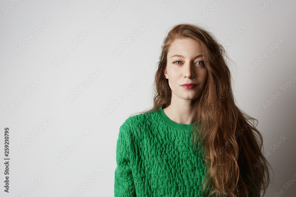 Youth and happiness female.Beautiful Caucasian teenage woman with long ginger hair and freckles, dressed casually, standing against blank white wall.Copy paste space, studio shot, model.