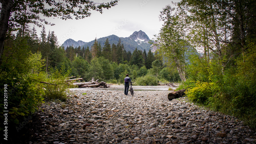 Man walking his bike toward a mountain Man walking his bike toward a mountain