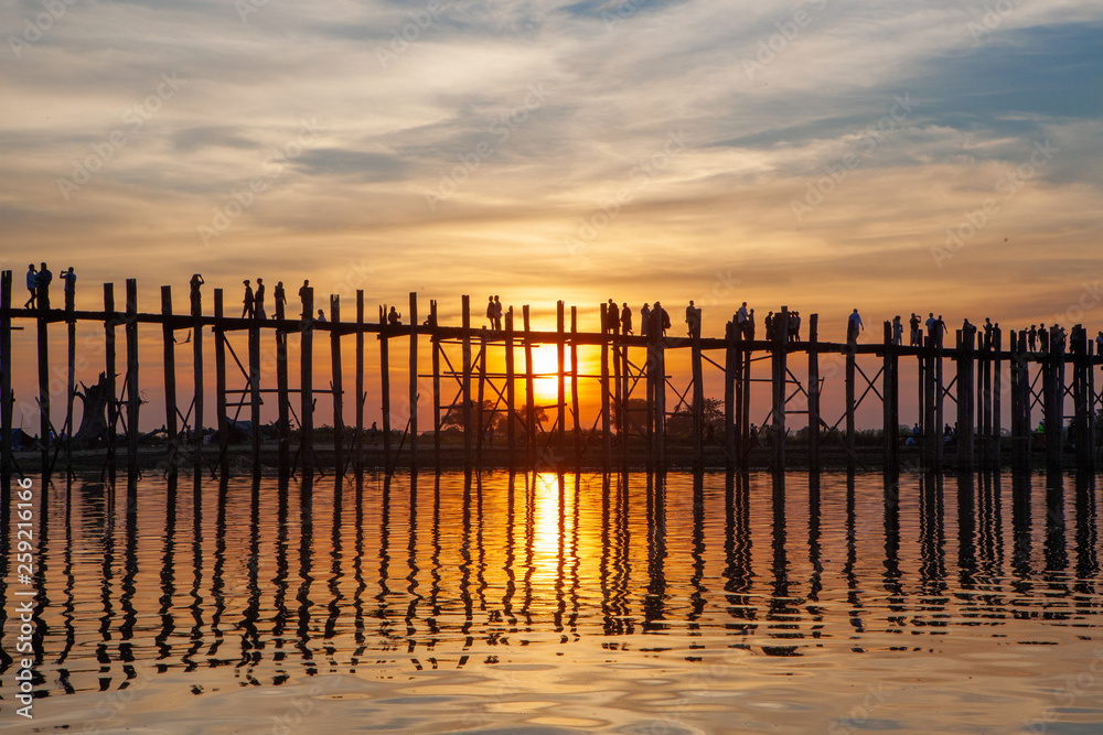 Sunset over U Bein Wooden bridge with locals' and tourists' silhouettes, Mandalay, Myanmar