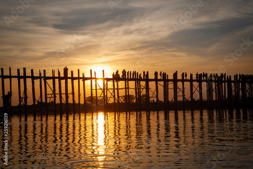 Sunset over U Bein Wooden bridge with locals' and tourists' silhouettes, Mandalay, Myanmar