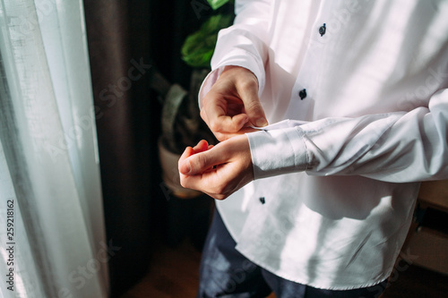 People, business,fashion and clothing concept - close up of man in shirt dressing up and adjusting tie on neck at home.