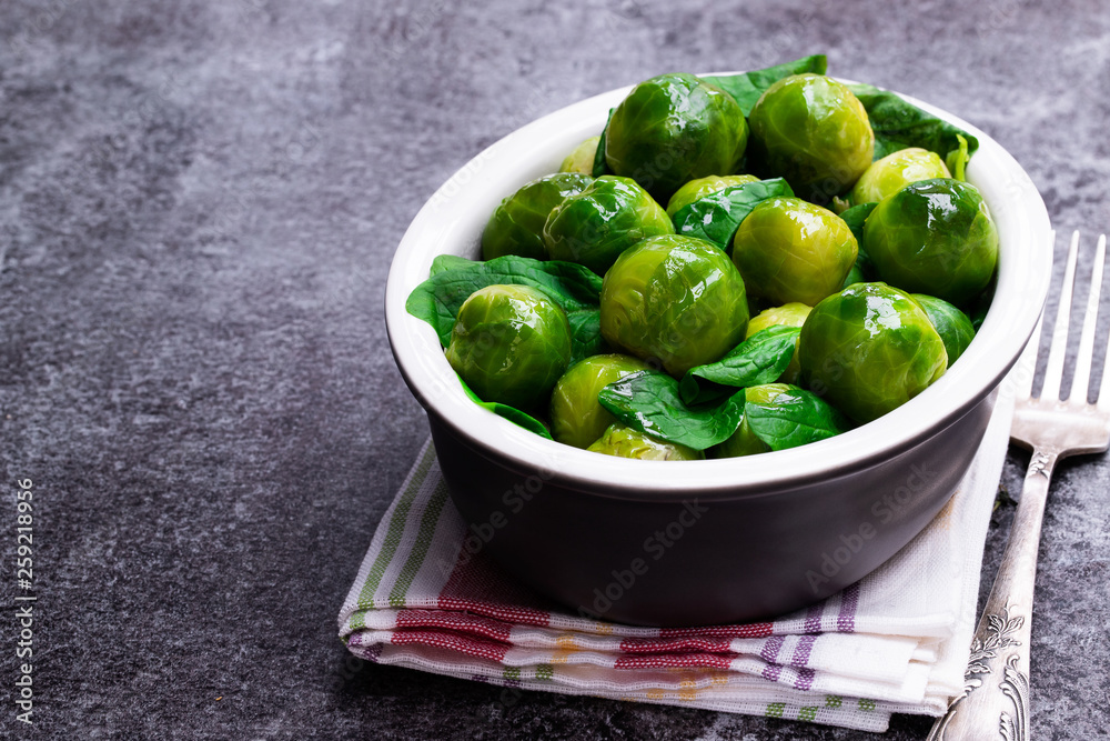 Cooked brussels sprouts with spinach on gray table Cooked brussels sprouts with spinach on gray table