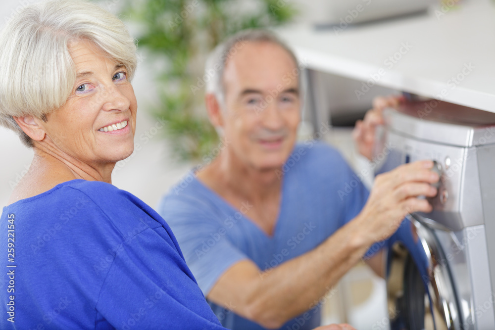 senior couple using washing machine senior couple using washing machine