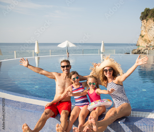 Obraz na płótnie Portrait of happy family with kids near swimming pool on resort w salonie