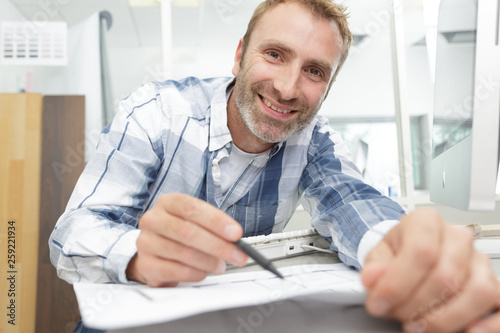 man leaning across computer keyboard to show paperwork