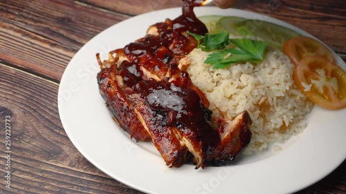 pouring sauce on the grilled chicken with rice. 
