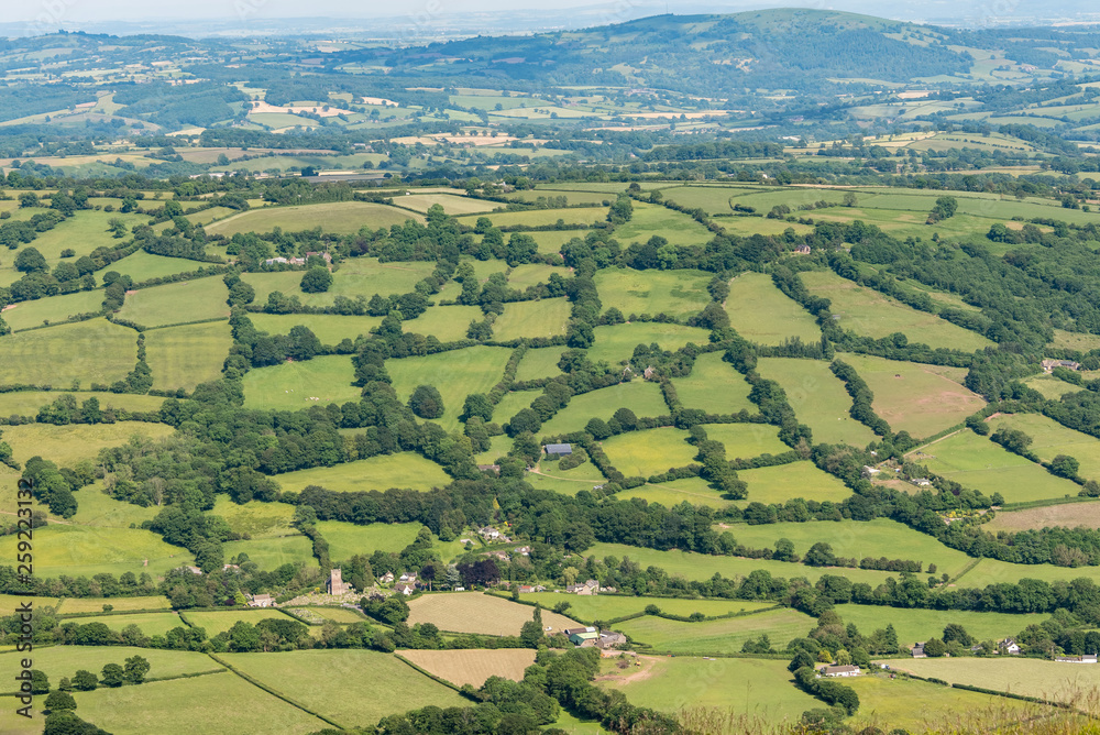 An English rural scene. It is a view of a patchwork of fields surrounded by green hedges, taken from above. The photo was taken from the Offa’s Dyke Path, on the Welsh border.