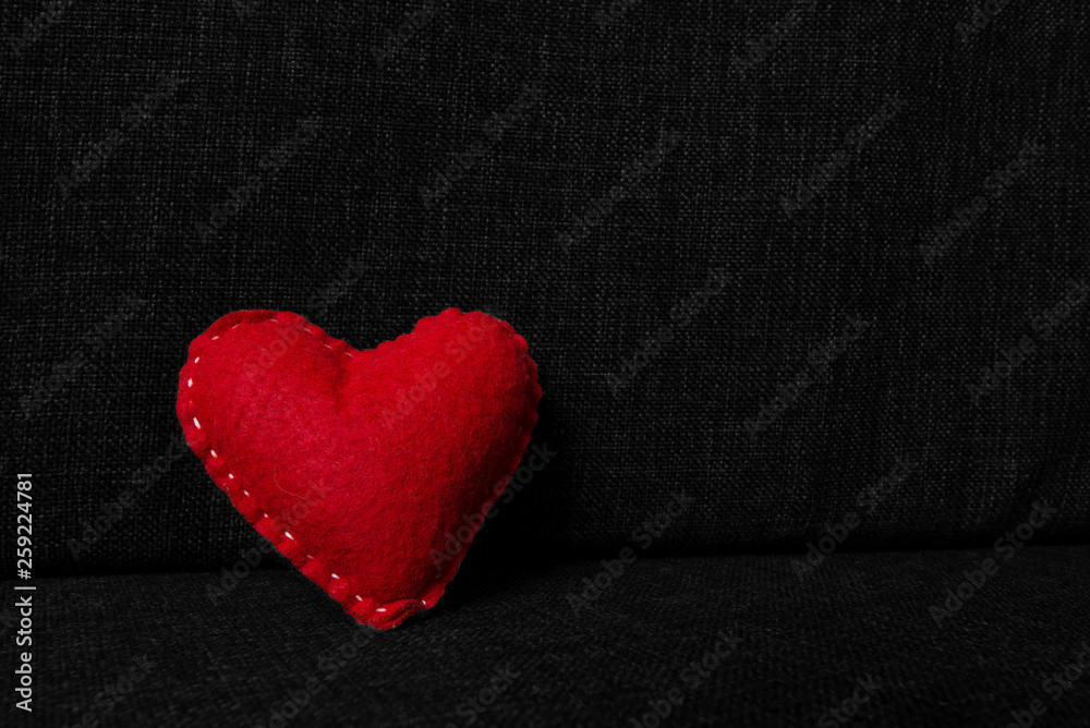 Obraz premium Red valentines day heart made from wool on dark fabric background. Concept of love