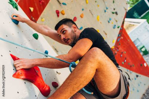 Young sporty man climbing up on practice mount wall outdoor