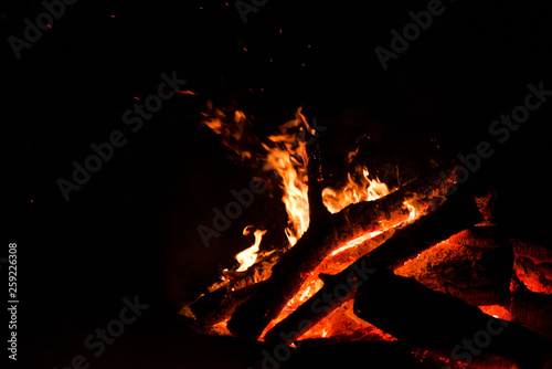 Large burning bonfire with soft glowing flame and sparkles flying all around. Romantic summer evening, people relaxing and enjoying calmness at the seaside during the Night of ancient lights