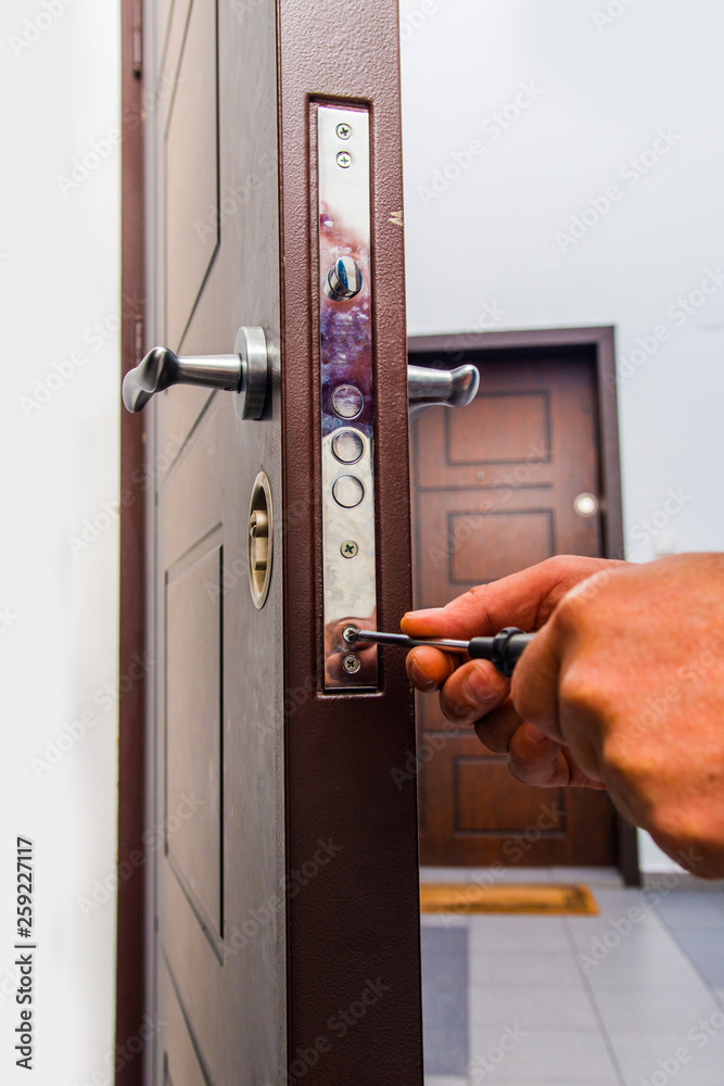 Workman standing near the door and fixing it Workman standing near the door and fixing it
