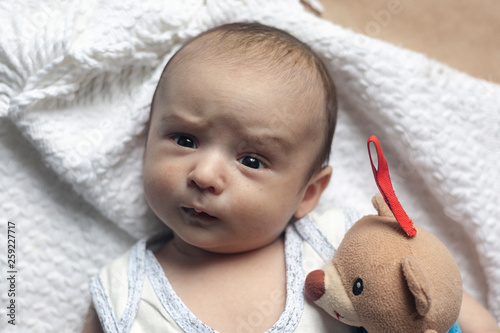 2 month baby boy lying. Close-up of adorable cute newborn baby boy of two months. Baby with suspicious face. Serious little kid. Emotional development in children.