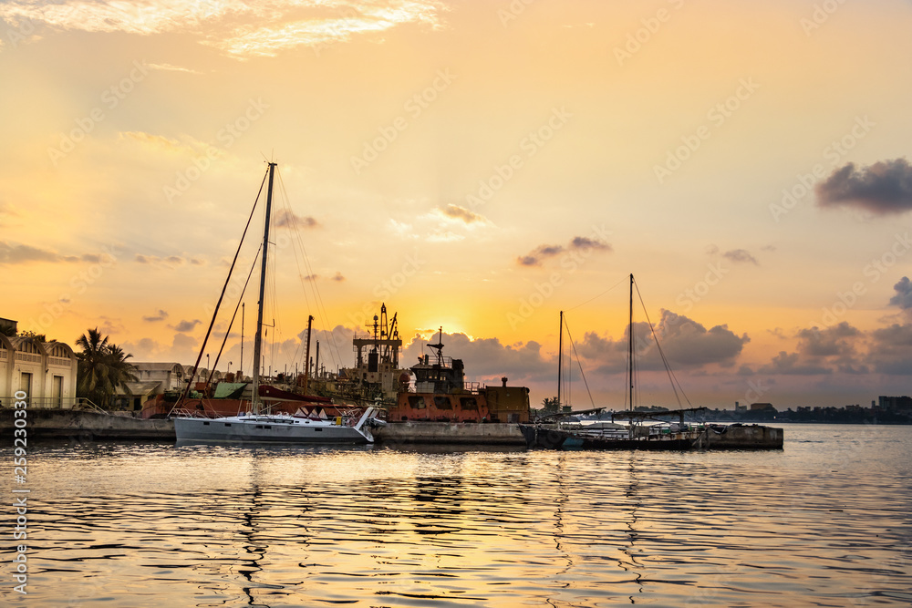 View of the Port of Galle at sunset with boats and rusty ships in the background in Sri Lanka.