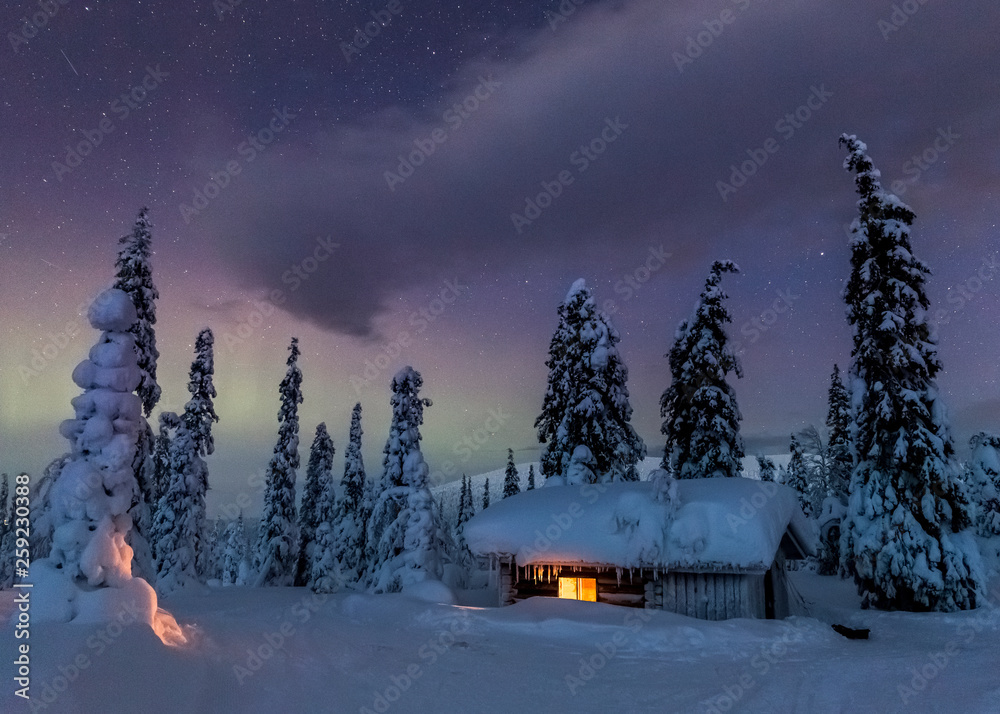 Light shines through window in snow covered cabin under colorful