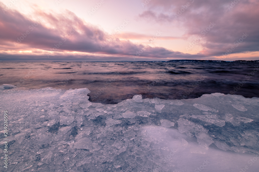 ice that has washed up on beach clouds and sunset in background ice that has washed up on beach clouds and sunset in background