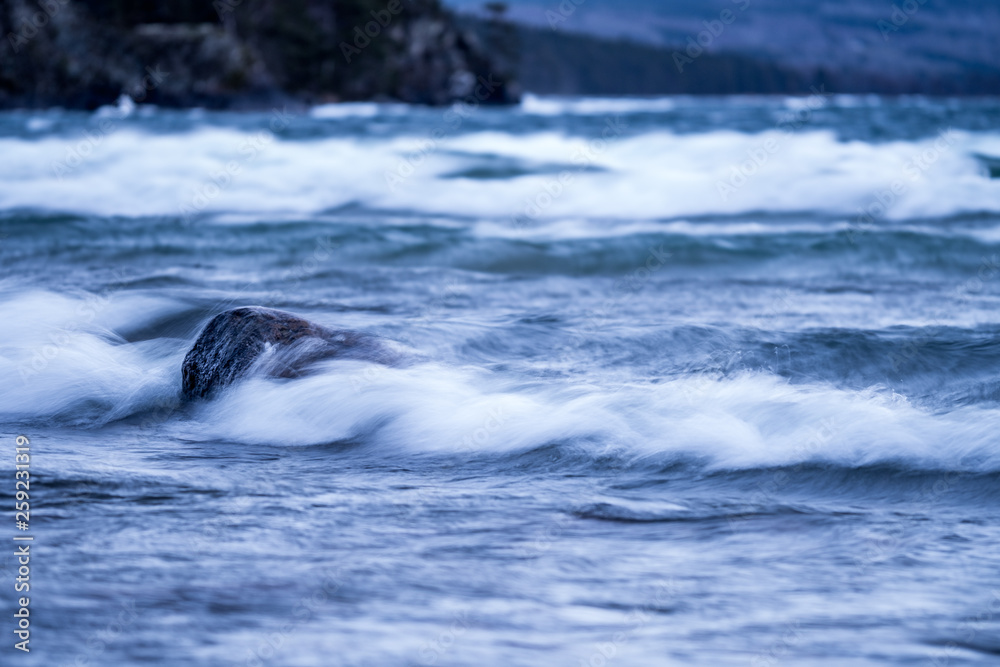 Fototapeta premium a wave embarking on a stone in the water