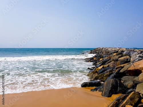 Waves crashing on breakwater rocks on a sandy tropical beach in Lagos, Nigeria. photo