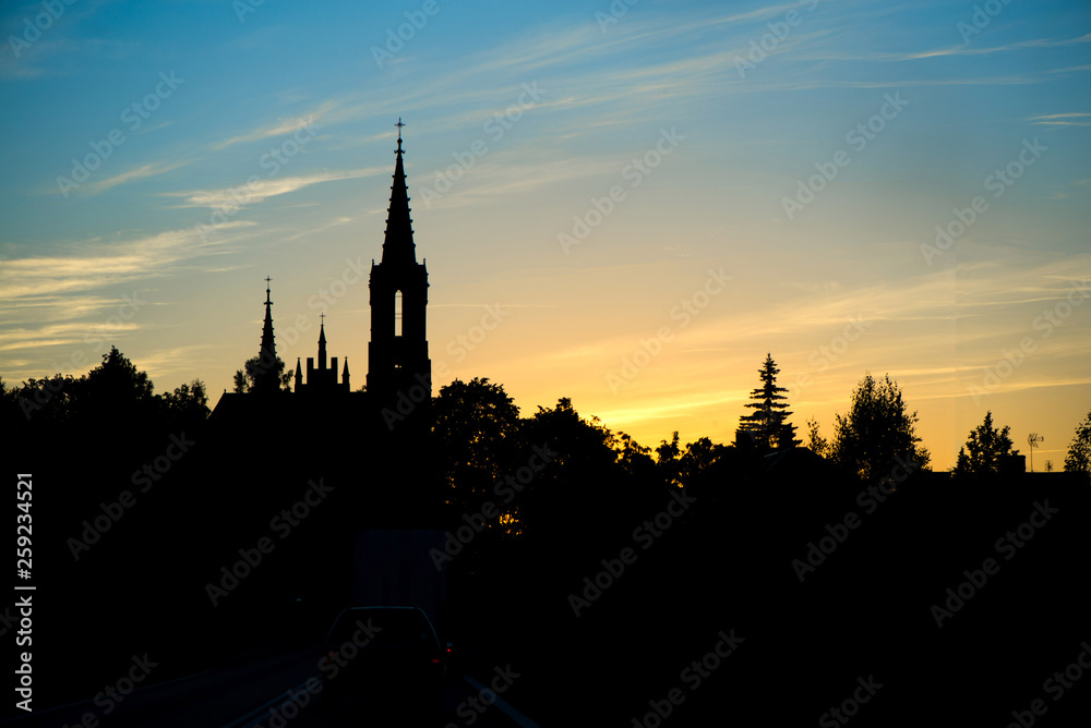 Silhouette of church and city on sunset or sunrise background. 