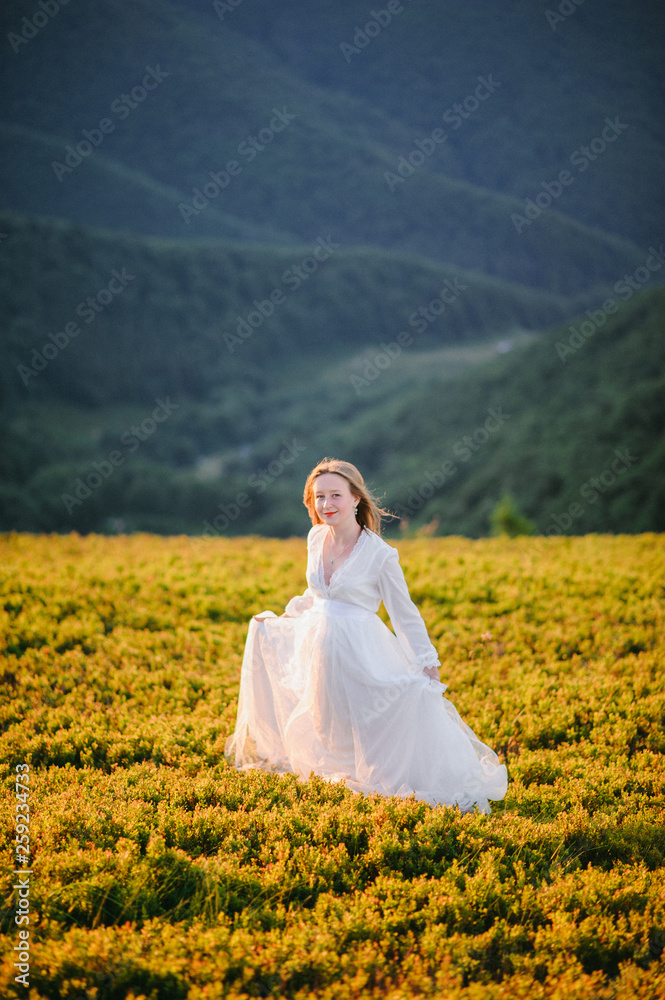 woman in a wedding dress runs across the field toward the mountains woman in a wedding dress runs across the field toward the mountains