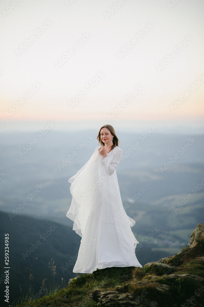 woman in a wedding dress runs across the field toward the mountains