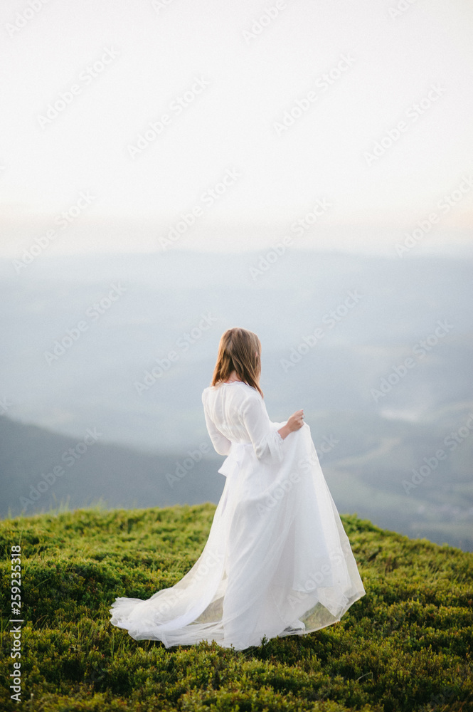 woman in a wedding dress runs across the field toward the mountains woman in a wedding dress runs across the field toward the mountains
