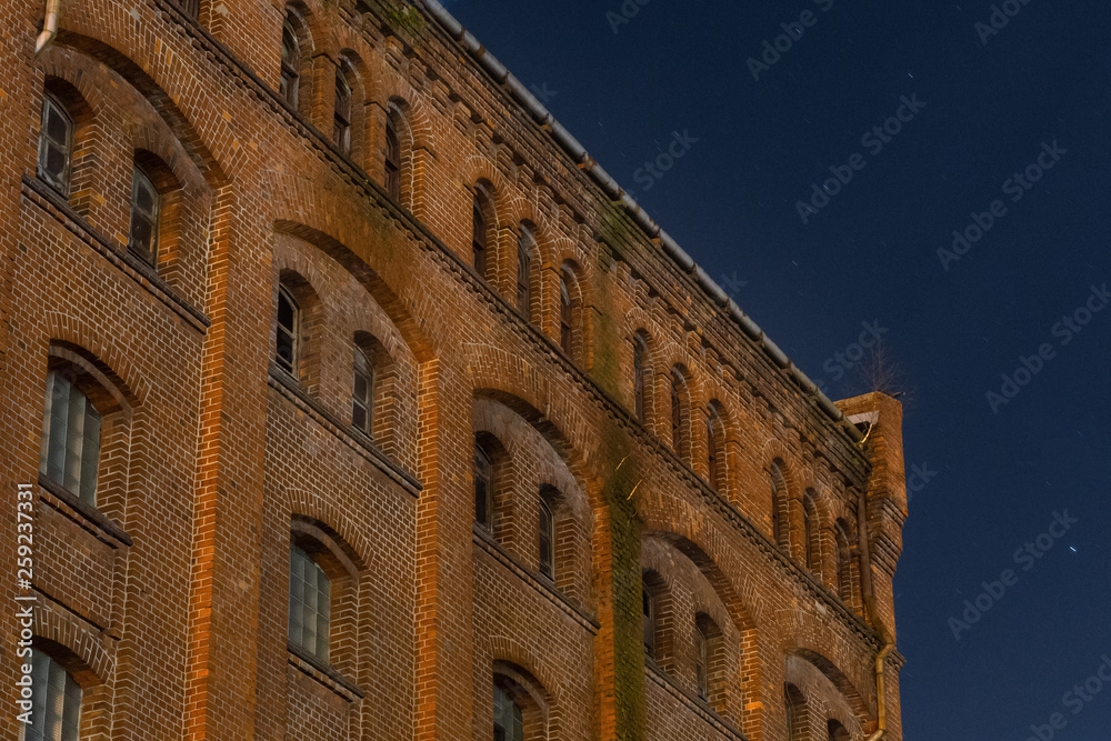 Facade of the old mill building at nighttime. Building of red brick