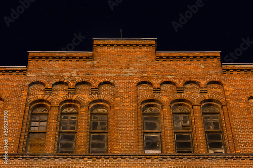 Facade of the old mill building at nighttime. Building of red brick