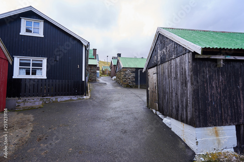 Small streets in pitoresque Faroese village Elduvík in deep fjord of the island Eysturoy during rainy cold day, one of Faroe islands, nice example of scandinavian or nordic style wooden architecture.