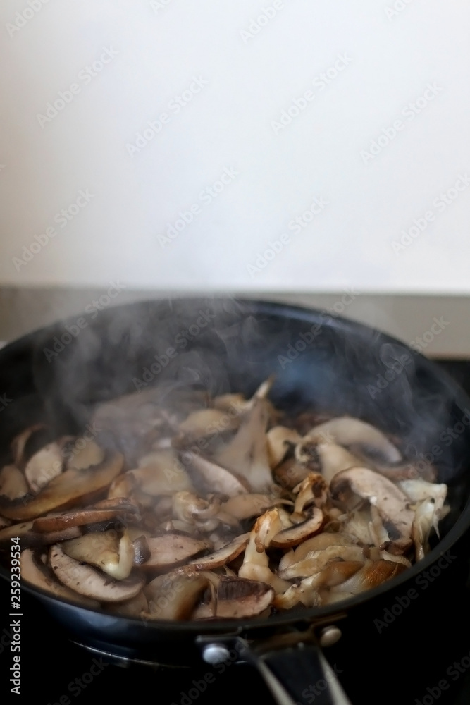 Frying oyster mushrooms and champignong in a pan with olive oil. Selective focus. Frying oyster mushrooms and champignong in a pan with olive oil. Selective focus.
