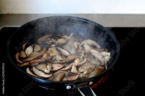 Frying oyster mushrooms and champignong in a pan with olive oil. Selective focus. 