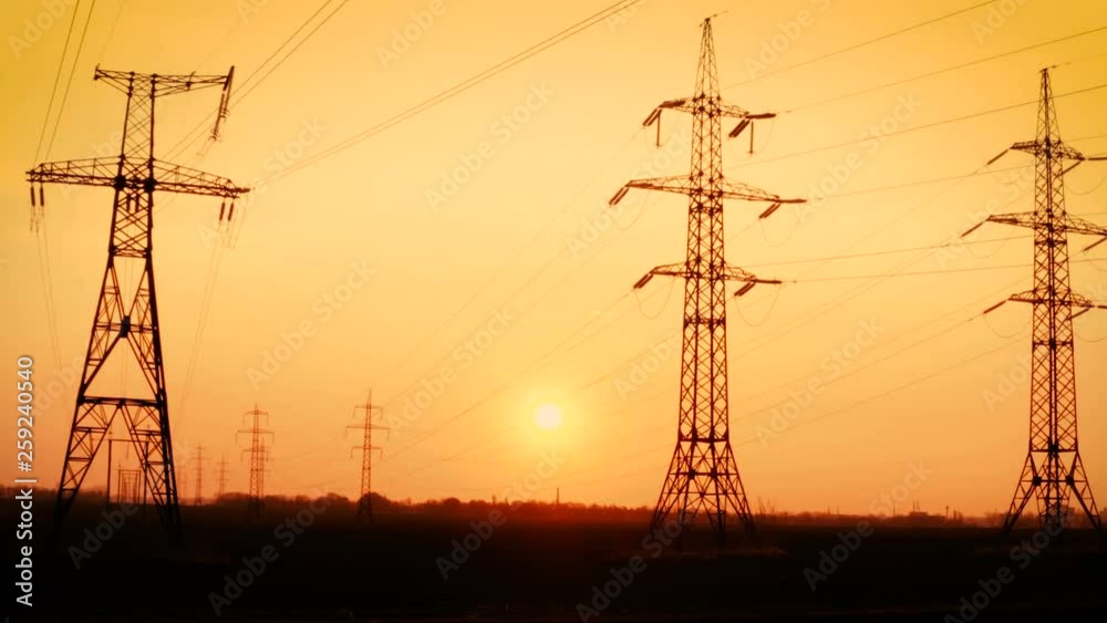 high voltage power lines at the field at the sunset time