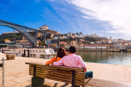 Porto, Portugal: A couple seating on a bench at Ribeira docks facing to Dom Luis I Bridge over Douro River and and Gaia town © -Marcus-