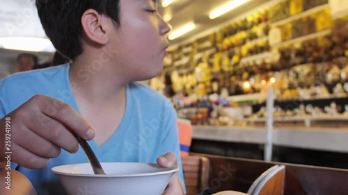 Happy asian child boy enjoy eating in Floating market is famous in Thailand, Damnoen Saduak popular floating market is about 100 km southwest of Bangkok in RATCHABURI province