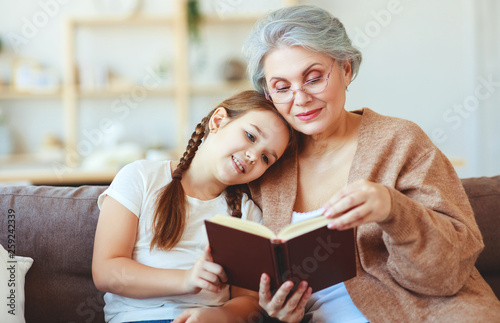 happy family grandmother reading to granddaughter book at home
