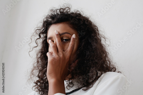 Young woman hiding her face behind her hand