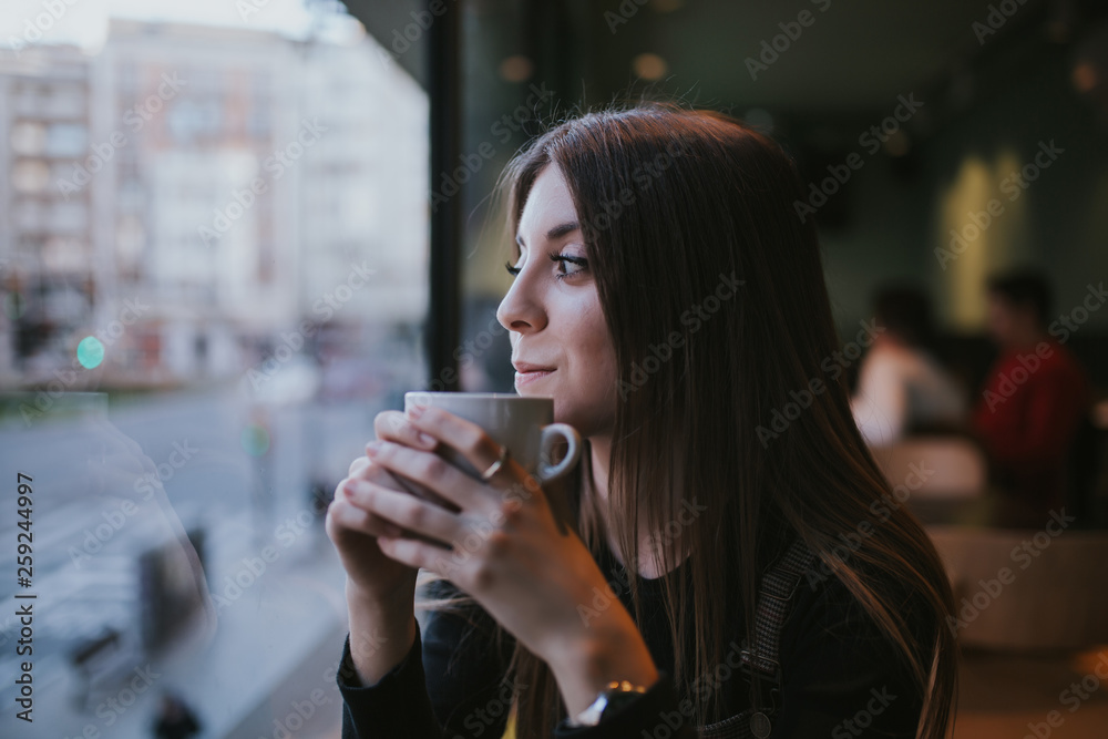 younger woman taking coffee at dusk younger woman taking coffee at dusk