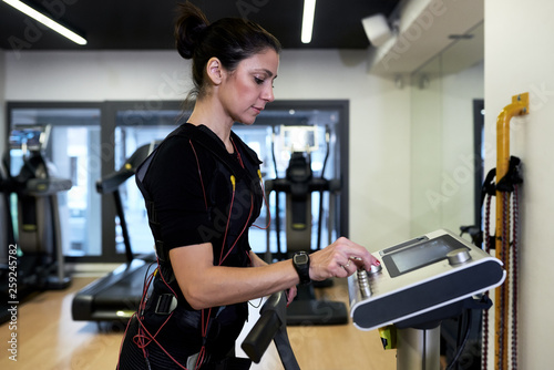 Sportswoman in bodytech vest on treadmill. photo