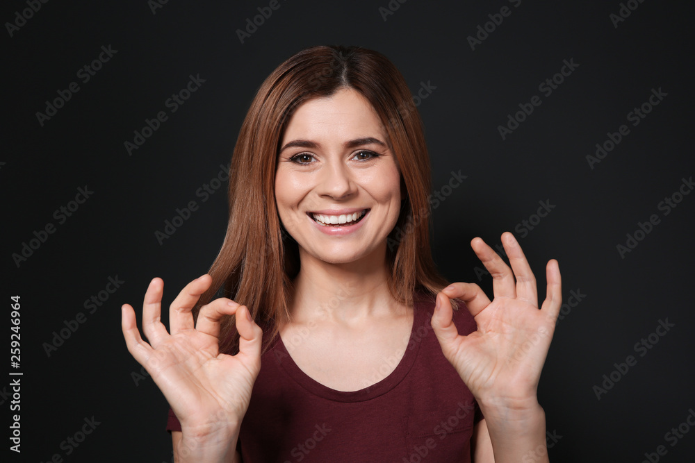 Woman showing OK gesture in sign language on black background Woman showing OK gesture in sign language on black background
