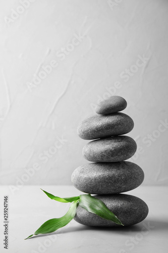 Stack of zen stones and bamboo leaves on table against light background. Space for text
