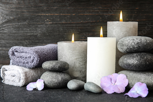 Composition with zen stones, towels and candles on table against wooden background