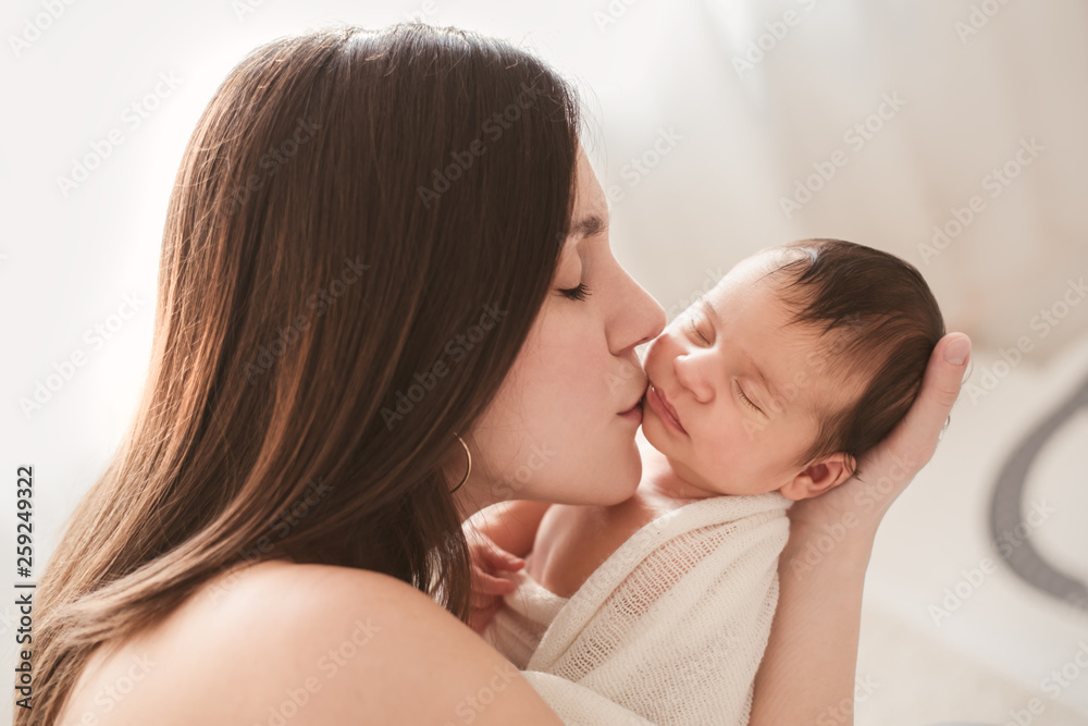 Loving mother kissing her newborn baby's cheek