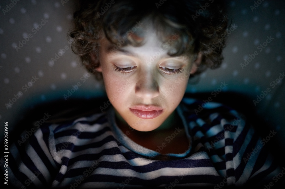 Kid reading ebook in bed. Kid reading ebook in bed.