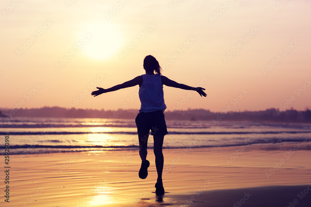 Happy Free Woman at Sunset on the Beach.