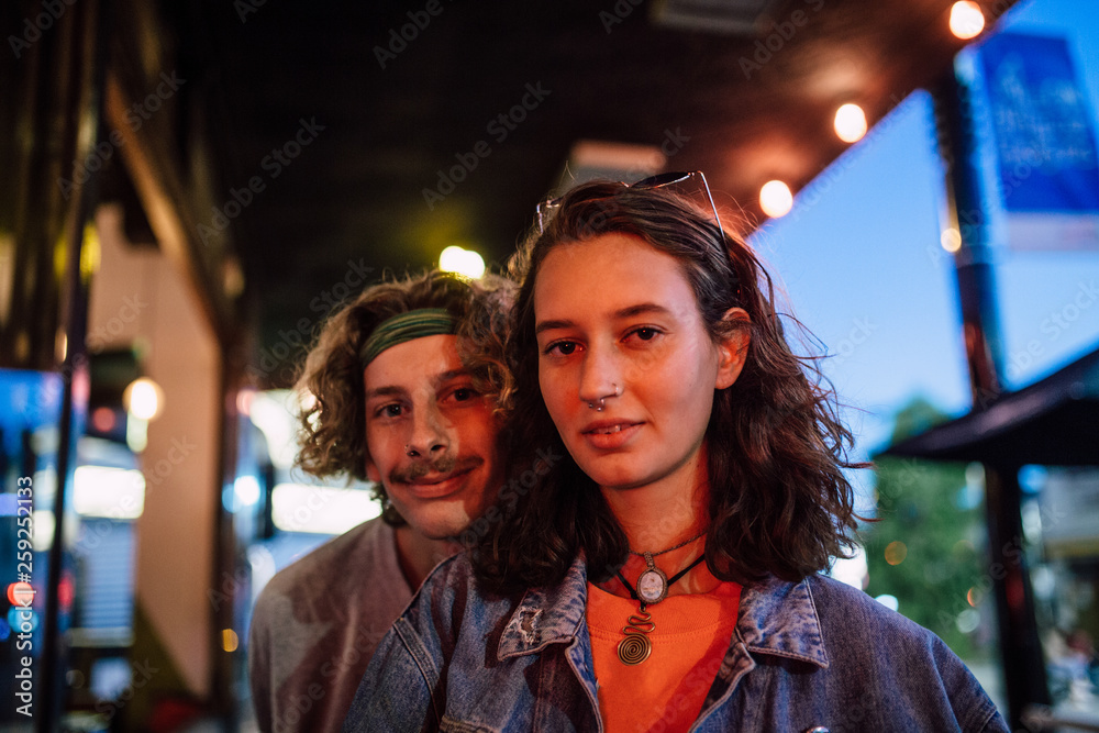 Couple standing in front of a bar lit by red light Couple standing in front of a bar lit by red light