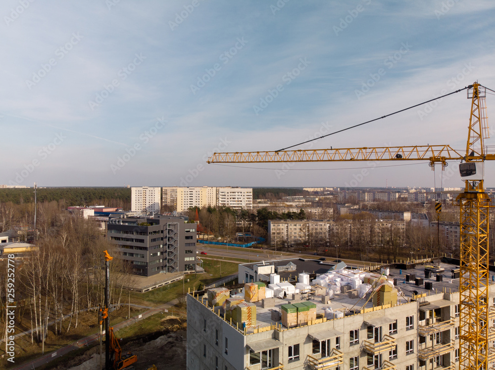 Aerial of a building site with a large operating bright yellow crane near a house