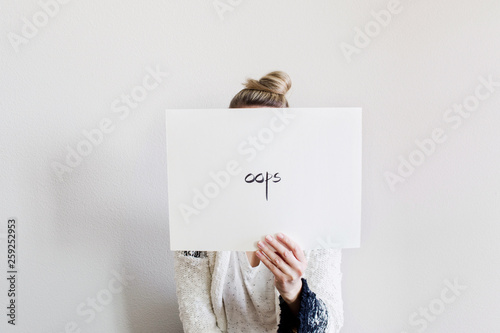 woman behind a paper with the word 