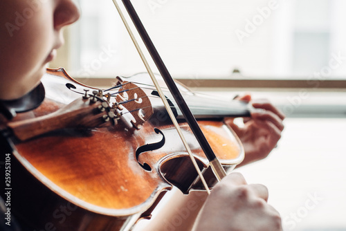 Young girl practicing violin by a window photo