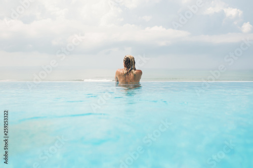 Rear view of woman in infinity pool