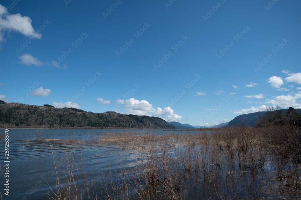 Low Angle View of Large Lake with Sunny Skies with Large Mountains Formation in the background