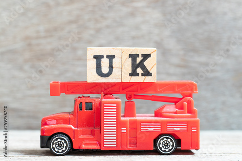 Red fire truck hold letter block in word UK  abbreviation of united kingdom  on wood background